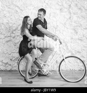 Immagine in bianco e nero di felice coppia giovane in amore seduti sulla bicicletta retrò allo studio Foto Stock