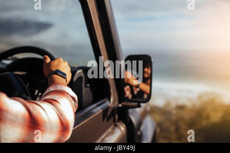 Immagine ritagliata dell uomo alla guida di auto. Focus sulla mano di un uomo con smart guarda sul volante del veicolo. Foto Stock