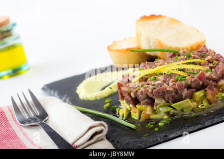 Il tonno rosso tartare di tonno su un nero ardesia piastra con avocado, servita con pane grigliato. Foto Stock