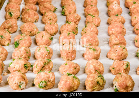 Appena formati polpette di greggio con erbe aromatiche sulla teglia da forno pronto per cuocere al forno Foto Stock