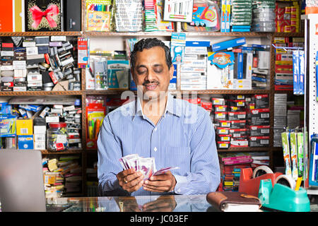 1 indian negoziante uomo conteggiare denaro contante in negozio stazionario Foto Stock