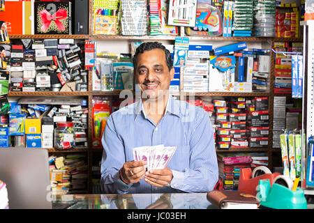 1 indian negoziante uomo conteggiare denaro contante in negozio stazionario Foto Stock
