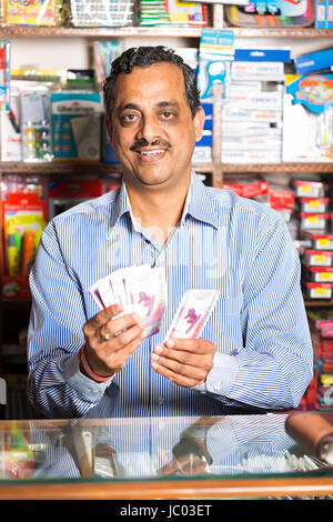 1 indian negoziante man standing contatore e conteggiare denaro contante in negozio stazionario Foto Stock