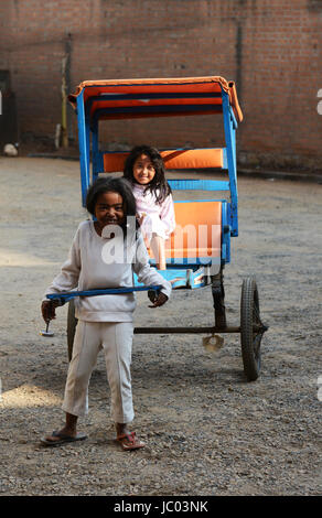 Cute ragazze malgasce giocando con un pousse pousse nel cortile di casa loro. Foto Stock