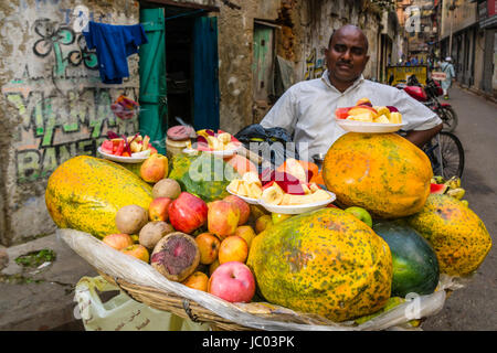 Un uomo è la vendita di frutta in un affollato mercato ortofrutticolo Street nel quartiere nuovo mercato Foto Stock