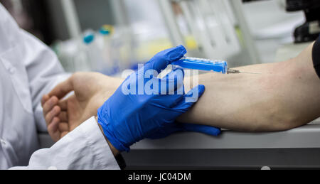 Medico o scienziato di iniettare un ago nel braccio del paziente Foto Stock