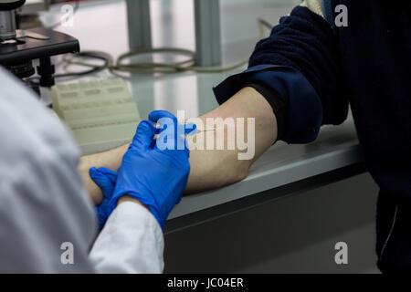 Medico o scienziato di iniettare un ago nel braccio del paziente Foto Stock