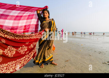 Le donne sono la sua essiccazione sari sulla spiaggia di ganga sagar, celebrando i maghi purnima festival Foto Stock