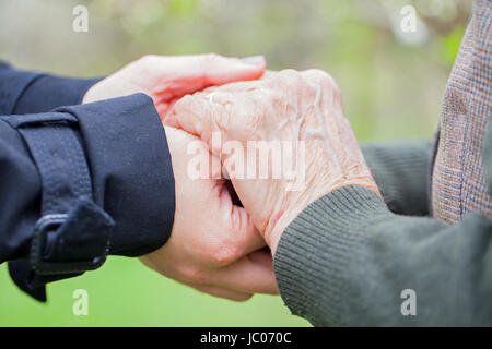 Chiudere l immagine di una giovane donna di mani tenendo un anziana donna mani Foto Stock