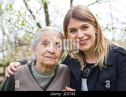 Fotografia di una donna anziana con allegro caregiver all'aperto nel giardino, primavera Foto Stock