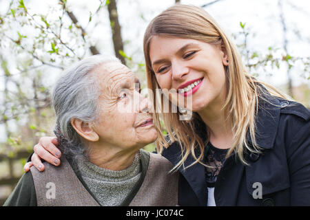 Fotografia di una donna anziana con allegro caregiver all'aperto nel giardino, primavera Foto Stock