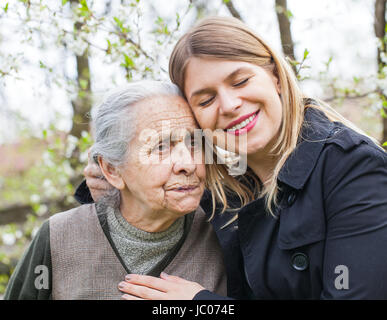 Fotografia di una donna anziana con allegro caregiver all'aperto nel giardino, primavera Foto Stock