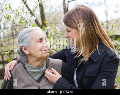 Fotografia di una donna anziana con allegro caregiver all'aperto nel giardino, primavera Foto Stock