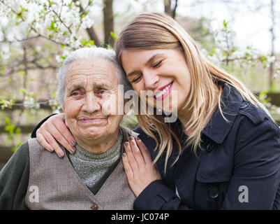 Fotografia di una donna anziana con allegro caregiver all'aperto nel giardino, primavera Foto Stock