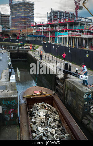 Chiatta in barca stretta piena di macerie di roccia passando attraverso la chiusa del canale di Camden Regents Foto Stock