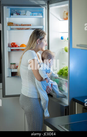 Ritratto di madre e bambino figlio per cercare qualcosa da mangiare in frigo durante la notte Foto Stock