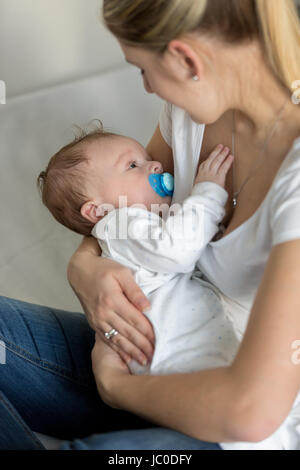 Giovane e bella madre di lei a dondolo simpatico baby sulle mani Foto Stock