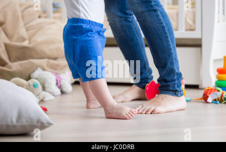 Primo piano della adorabile del bambino e la madre con i piedi sul pavimento a soggiorno Foto Stock