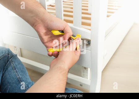 Closeup foto di un uomo lo smontaggio di bianco letto in legno Foto Stock