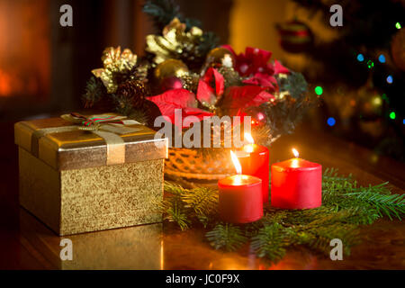 Bella candele accese dall'albero di Natale decorato, giftbox e il tradizionale omaggio floreale Foto Stock