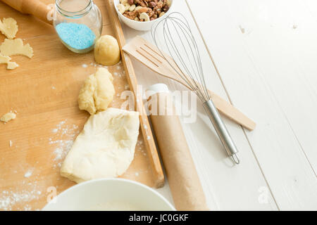 Primo piano della pasta fresca giacente sulla scrivania di legno accanto a utensili Foto Stock