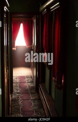 Interno del lussuoso treno vintage con un lungo corridoio e tendaggi rossi su windows Foto Stock