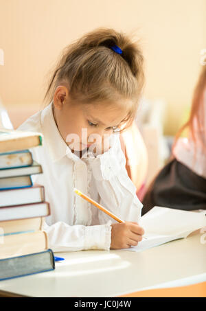 Closeup Ritratto di ragazza triste esercizio di scrittura in un libro di testo di una scuola Foto Stock