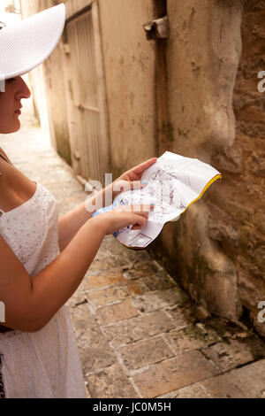 Primo piano della donna perse in città vecchia puntando alla mappa Foto Stock