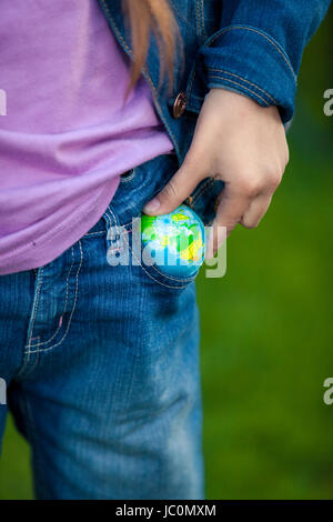 Closeup foto concettuale della ragazza globo mettendo in tasca Foto Stock