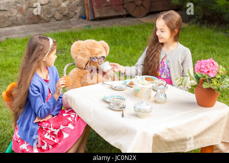 Due ragazze avente tea party con Teddy bear in cantiere Foto Stock
