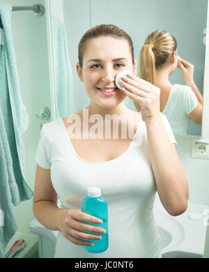 Ritratto di bella donna sorridente usando lozione idratante a bagno Foto Stock