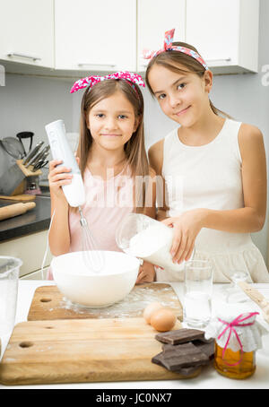 Ritratto di due sorella miscelazione degli ingredienti per la pasta nella grande ciotola da cucina Foto Stock