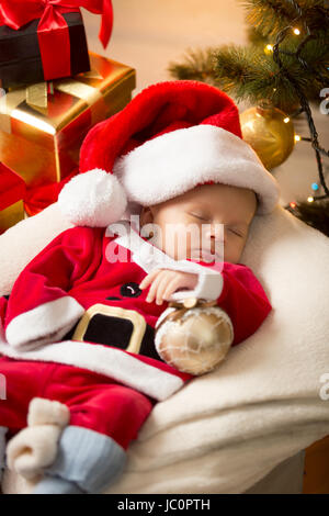 Ritratto di simpatici baby boy in Santa costume sleeping ext per i regali di Natale Foto Stock