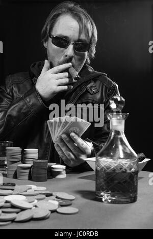 Foto di un uomo giocando a poker indossando occhiali da sole e fumare un sigaro. Foto Stock