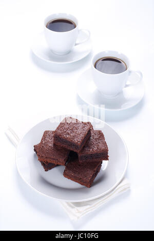 Brownie al cioccolato sulla piastra bianca e due tazze di caffè Foto Stock