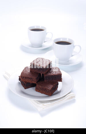Brownie al cioccolato sulla piastra bianca e due tazze di caffè Foto Stock
