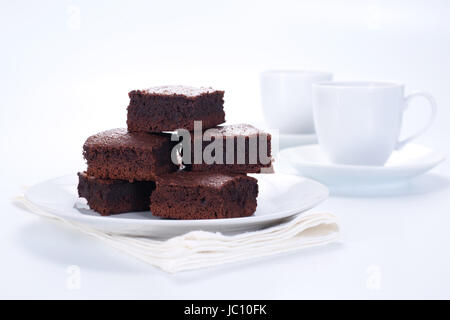 Brownie al cioccolato sulla piastra bianca e due tazze di caffè Foto Stock