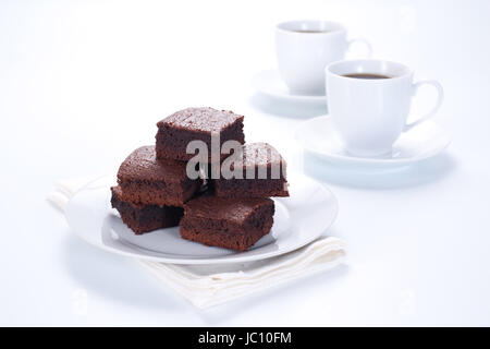 Brownie al cioccolato sulla piastra bianca e due tazze di caffè Foto Stock