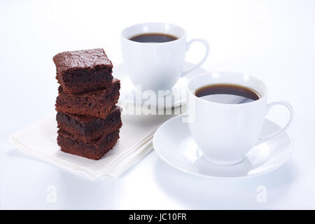 Brownie al cioccolato sulla piastra bianca e due tazze di caffè Foto Stock