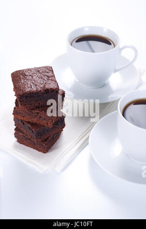 Brownie al cioccolato sulla piastra bianca e due tazze di caffè Foto Stock