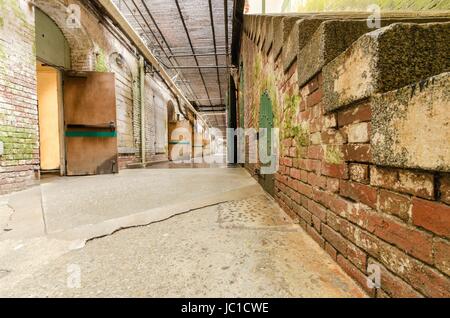 Il tunnel sotterraneo e dungeons sotto il Cellhouse sul penitenziario di Alcatraz island, ora un museo, a San Francisco, California, Stati Uniti d'America. Una vista di una scala, pareti di mattoni e pesanti porte di ferro per le cellule. Foto Stock