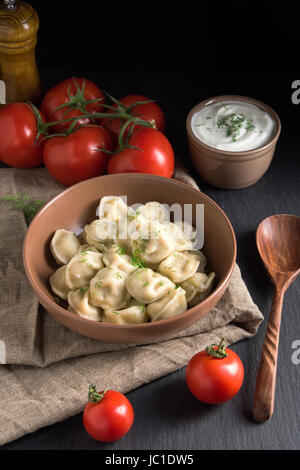 Canederli di carne servita con pomodori e panna acida sulla pietra nera sullo sfondo Foto Stock