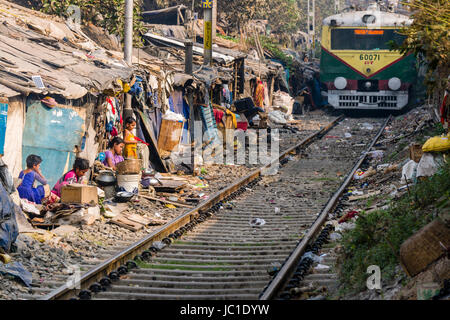 Il numero di abitazioni e di capanne in Cina Bazar delle baraccopoli sono situati proprio accanto ai binari della ferrovia, un treno è passante Foto Stock