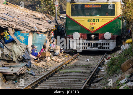 Il numero di abitazioni e di capanne in Cina Bazar delle baraccopoli sono situati proprio accanto ai binari della ferrovia, un treno è passante Foto Stock