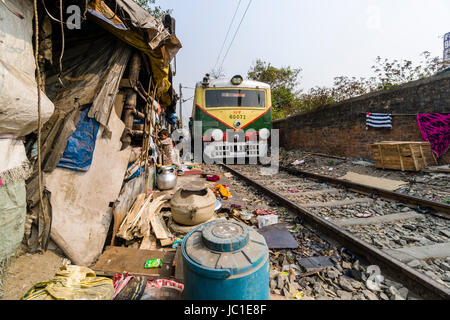 Il numero di abitazioni e di capanne in Cina Bazar delle baraccopoli sono situati proprio accanto ai binari della ferrovia, un treno è passante Foto Stock