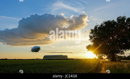 Cardington, Bedfordshire, Regno Unito. Xiii Giugno, 2017. L'aria ibride Veicoli Airlander 10 continua la sua 2017 Programma di prove in volo. Di decollare con calma secco meteo con sole e poco cloud a Cardington Airfield ha fatto grandi circuiti della campagna locale con tre touch and go passa in corrispondenza della zona di ormeggio prima di approdare definitivamente come il sole è andato giù. Ripida salita con il dirigibile gigante hangar in background. Photo credit: Mick Flynn/Alamy Live News Foto Stock