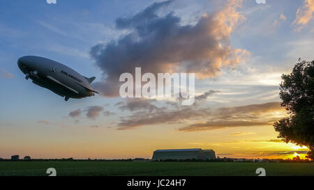 Cardington, Bedfordshire, Regno Unito. Xiii Giugno, 2017. L'aria ibride Veicoli Airlander 10 continua la sua 2017 Programma di prove in volo. Di decollare con calma secco meteo con sole e poco cloud a Cardington Airfield ha fatto grandi circuiti della campagna locale con tre touch and go passa in corrispondenza della zona di ormeggio prima di approdare definitivamente come il sole è andato giù. Ripida salita con il dirigibile gigante hangar in background. Photo credit: Mick Flynn/Alamy Live News Foto Stock