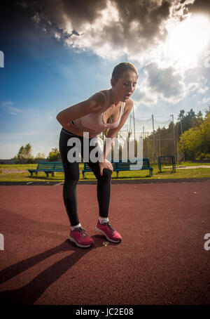 Stanco della donna in appoggio dopo aver eseguito sullo sport arena ad acqua calda giornata di sole Foto Stock