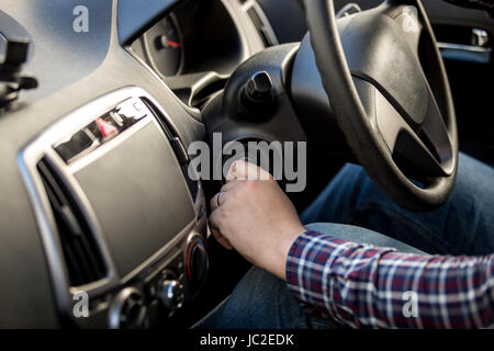 Driver maschio girando la chiave di accensione nell'auto con guida a destra Foto Stock