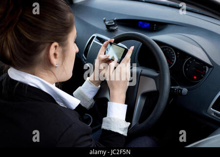 Giovane imprenditrice utilizza lo smartphone durante la guida auto Foto Stock